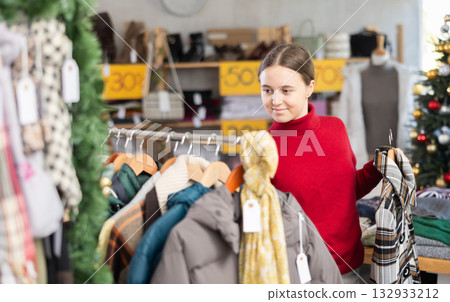 In sales area of store during Christmas sale, teen girl customer choose coat or jacket In sales area of store during Christmas sale, teen girl customer choose coat or jacket 132933212