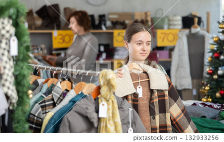 In sales area of store during Christmas sale, teen girl customer choose plaid jacket In sales area of store during Christmas sale, teen girl customer choose plaid jacket 132933256