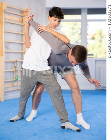 Teenage boy and middle-aged man training arm twist technique during self-defense courses Teenage boy and middle-aged man training arm twist technique during self-defense courses 132933271