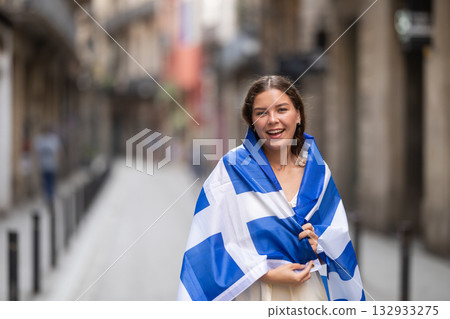 Woman waving Greek flag on street of summer European city Woman waving Greek flag on street of summer European city 132933275
