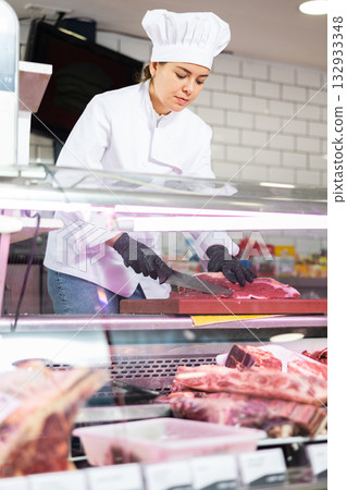 Female butcher slicing raw beef fillet for customer 132933348