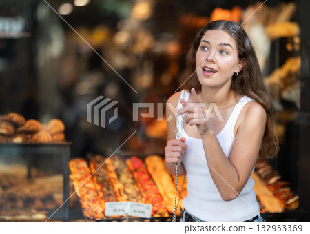 Female tourist near window of street cafe food court choosing a traditional Catalan sandwich coca with filling Female tourist near window of street cafe food court choosing a traditional Catalan sandwich coca with filling 132933369