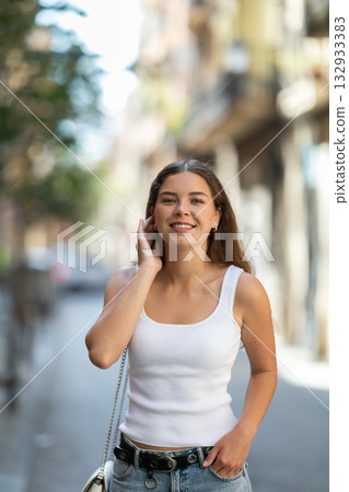 Young woman walks through streets of historic city center. On bright summer day, tourist girl looks at old buildings Young woman walks through streets of historic city center. On bright summer day, tourist girl looks at old buildings 132933383
