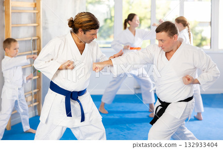 Man father is paired with coach to learn how to strike and rehearses blocking opponent 132933404