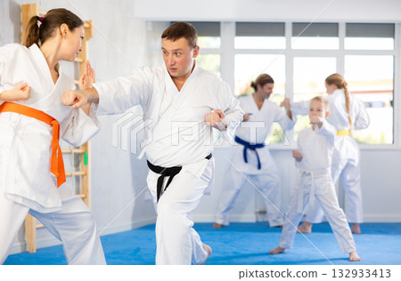 Woman is paired with man teacher to learn how to strike and rehearses blocking opponent Woman is paired with man teacher to learn how to strike and rehearses blocking opponent 132933413