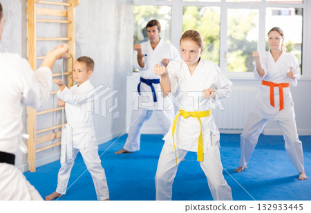 Teen girl with family repeat movements and learn fighting techniques during martial arts lesson Teen girl with family repeat movements and learn fighting techniques during martial arts lesson 132933445