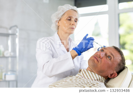 Man applying rejuvenating treatments by female doctor. 132933486