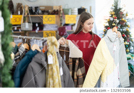 Teenage girl chooses coat or jacket in clothing store 132933506