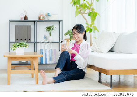 A young woman operating a smartphone in a room A young woman operating a smartphone in a room 132933676