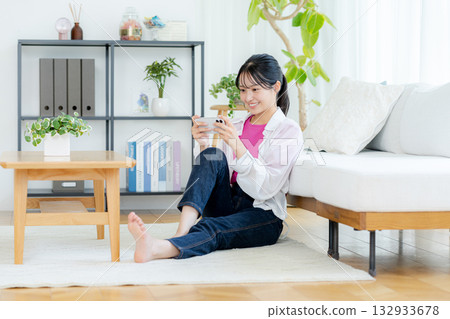 A young woman operating a smartphone in a room A young woman operating a smartphone in a room 132933678