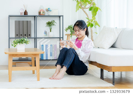A young woman operating a smartphone in a room A young woman operating a smartphone in a room 132933679