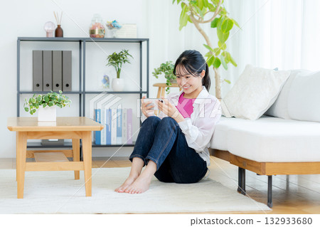A young woman operating a smartphone in a room A young woman operating a smartphone in a room 132933680