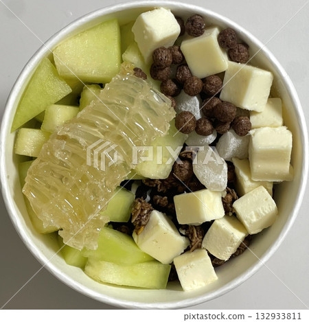 Swirled yogurt ice cream dessert served in a cup, smooth creamy texture with glossy surface, topped with fresh fruit pieces, highlighting its refreshing and inviting appearance in detail Swirled yogurt ice cream dessert served in a cup, smooth creamy texture with glossy surface, topped with fresh fruit pieces, highlighting its refreshing and inviting appearance in detail 132933811