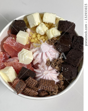 Swirled yogurt ice cream dessert served in a cup, smooth creamy texture with glossy surface, topped with fresh fruit pieces, highlighting its refreshing and inviting appearance in detail Swirled yogurt ice cream dessert served in a cup, smooth creamy texture with glossy surface, topped with fresh fruit pieces, highlighting its refreshing and inviting appearance in detail 132933815