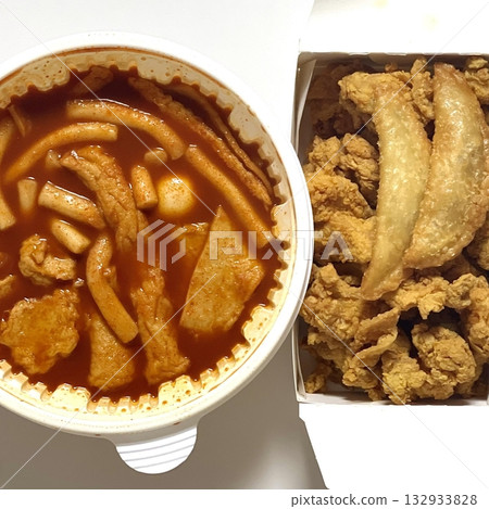 Spicy yeoptteok paired with crispy Korean fried chicken, combining fiery rice cakes and savory crunch for an irresistible duo that’s bold, satisfying, and full of Korean street food flavor. 132933828