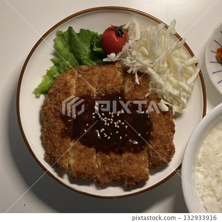 Crispy tonkatsu, a Japanese-style breaded and deep-fried pork cutlet, served with shredded cabbage and drizzled with savory sauce. A delightful balance of crunchy texture and juicy meat. Crispy tonkatsu, a Japanese-style breaded and deep-fried pork cutlet, served with shredded cabbage and drizzled with savory sauce. A delightful balance of crunchy texture and juicy meat. 132933916