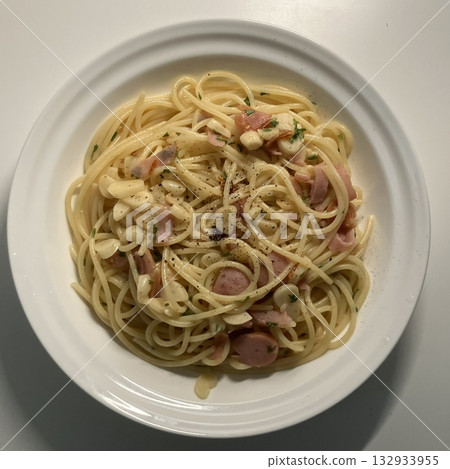 A plate of spaghetti pasta, perfectly cooked and topped with rich marinara sauce and fresh herbs. Ideal for food photography and menus, capturing the heart of Italian cuisine in a delicious way. 132933955