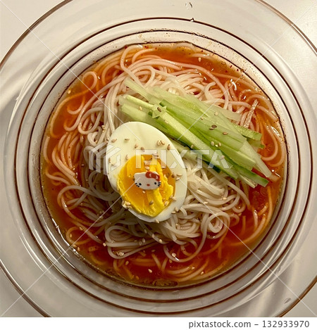 Chilled, chewy naengmyeon noodles in tangy broth paired with juicy, savory mandu dumplings, offering a perfect balance of refreshing coolness and hearty comfort in every delicious Korean bite. 132933970