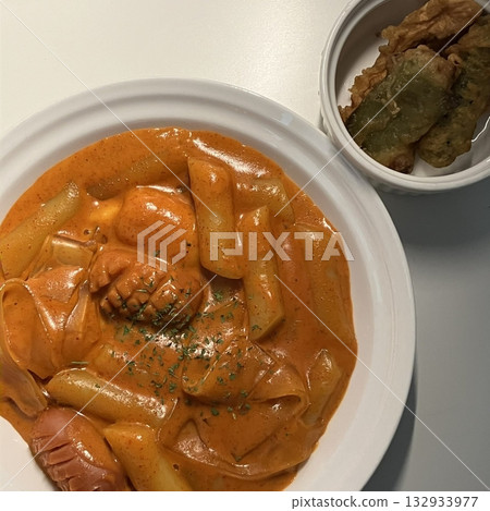 Spicy Korean tteokbokki with chewy rice cakes in a vibrant red sauce, topped with sesame seeds and green onions. A popular street food known for its addictive flavor and satisfying texture. 132933977