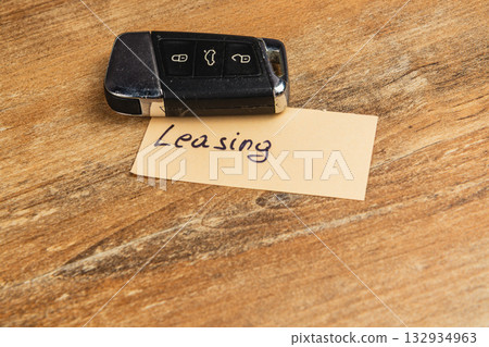 Key fob placed on paper labeled leasing on wooden surface Key fob placed on paper labeled leasing on wooden surface 132934963