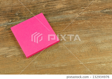 Bright pink sticky note on a wooden surface ready for writing reminders Bright pink sticky note on a wooden surface ready for writing reminders 132934976