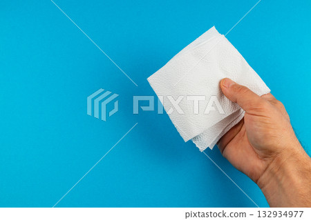 Hand holding several folded paper napkins against a blue background 132934977