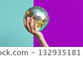 Hand holding a disco ball with vibrant colors, created AI 132935181
