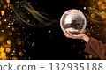 A hand holds a sparkling disco ball twinkling, created AI 132935188