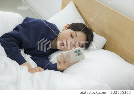A woman watching a smartphone in bed 132935363
