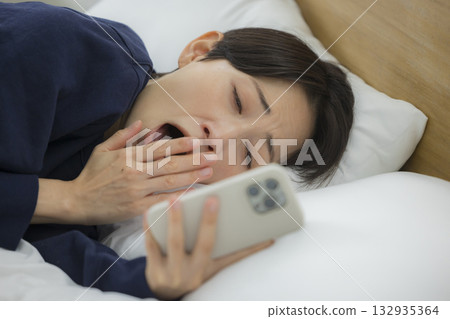 A woman watching a smartphone in bed A woman watching a smartphone in bed 132935364