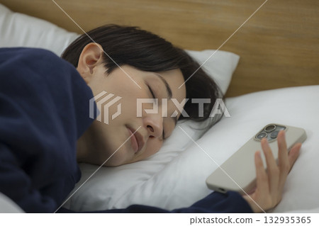 A woman watching a smartphone in bed A woman watching a smartphone in bed 132935365