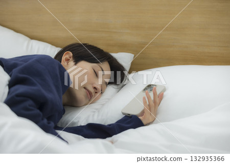 一名婦女在床上的看一個智能手機 132935366