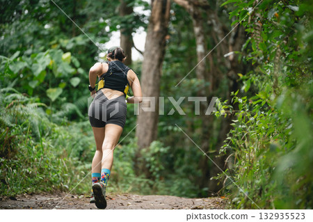 Female runner jogging through lush green forest path, enjoying nature, fitness journey, healthy lifestyle, athletic movement, outdoor exercise, peaceful environment Female runner jogging through lush green forest path, enjoying nature, fitness journey, healthy lifestyle, athletic movement, outdoor exercise, peaceful environment 132935523