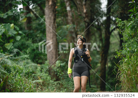 Woman Hiking on Forest Trail Surrounded by Lush Greenery in Daylight, Embracing Nature and Adventure on an Outdoor Journey 132935524