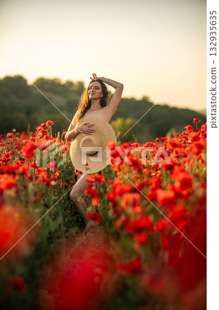 Woman in Poppy Field Holding Straw Hat 132935635