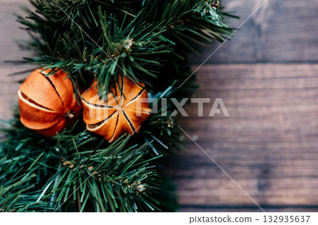 christmas background pine tree with dried tangerines wooden background. The combination of the pine tree, ornaments, and greenery creates a classic and cozy setting. christmas background pine tree with dried tangerines wooden background. The combination of the pine tree, ornaments, and greenery creates a classic and cozy setting. 132935637