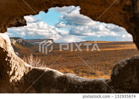 Cliffs forest sky view from cave opening overlooking vast autumnal landscape Cliffs forest sky view from cave opening overlooking vast autumnal landscape 132935674