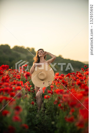 Woman in a Poppy Field Holding a Straw Hat Woman in a Poppy Field Holding a Straw Hat 132935692