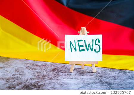 Paper note with words NEWS on National symbol of Germany. German wave silky flag background. News report headlines media Paper note with words NEWS on National symbol of Germany. German wave silky flag background. News report headlines media 132935707