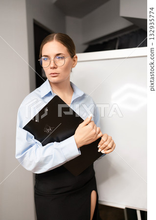 Businesswoman professional clipboard standing serious in office holding document folder near whiteboard 132935774
