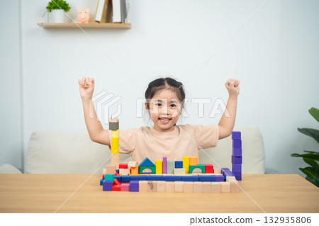 Joyful Child Celebrating Success with Colorful Building Blocks in a Bright and Inviting Indoor Space 132935806