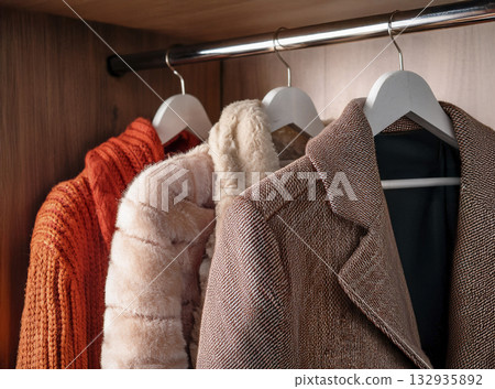 衣櫃裡有紅棕色的針織外套、夾克和毛衣。 衣櫃裡有紅棕色的針織外套、夾克和毛衣。 132935892