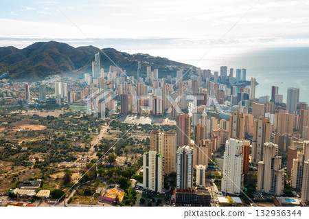 Panoramic landscape of Benidorm city with modern skyscrapers, palm-lined beaches, and crystal clear Mediterranean waters. Sunny Spanish coastal view with blue sky and sea horizon. 132936344