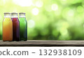 Colorful Bottles of Juice on Wooden Table with Blurred Green Background 132938109
