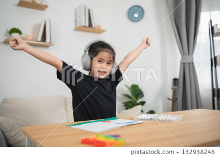 Happy Young Girl Enjoying Creative Activities at Home with Headphones and Bright Colors in a Cozy Living Room Setting 132938246