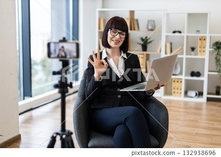 Confident Caucasian woman demonstrating business techniques on video, seated with laptop, indoors 132938696