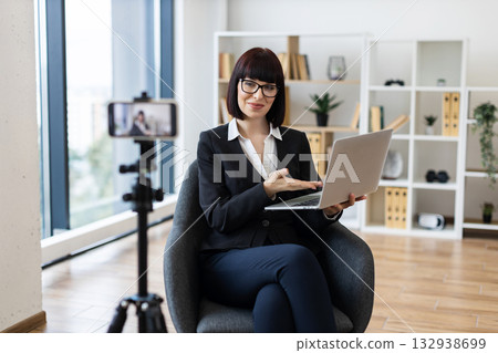 Caucasian woman, young adult, recording video blog with laptop indoors, discussing business. Caucasian woman, young adult, recording video blog with laptop indoors, discussing business. 132938699