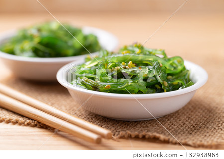 Wakame seaweed salad with sesame seed in a bowl with chopsticks 132938963
