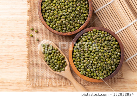 Mung bean in wooden bowl and scoop on wooden background, Asian food ingredient, Table top view Mung bean in wooden bowl and scoop on wooden background, Asian food ingredient, Table top view 132938984