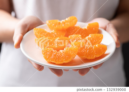 Fresh cut of Mandarin orange fruit on plate holding by hand ready to eating Fresh cut of Mandarin orange fruit on plate holding by hand ready to eating 132939008
